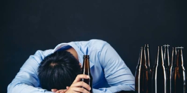 Cropped close up of a man drinking beer at the home