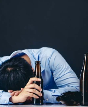 Cropped close up of a man drinking beer at the home